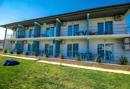 a building with blue windows and a green lawn at Casa Mavi in Vama Veche