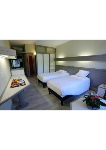 een hotelkamer met twee bedden en een tafel bij Hôtel Belleville in Lamalou-les-Bains