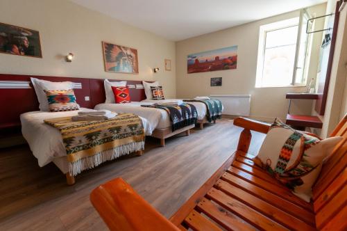 a room with three beds and a bench in it at Hotel Le Ranch in Brûlon