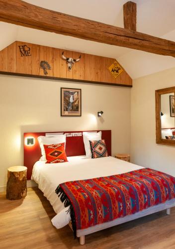 a bedroom with a large bed with a red blanket at Hotel Le Ranch in Brûlon