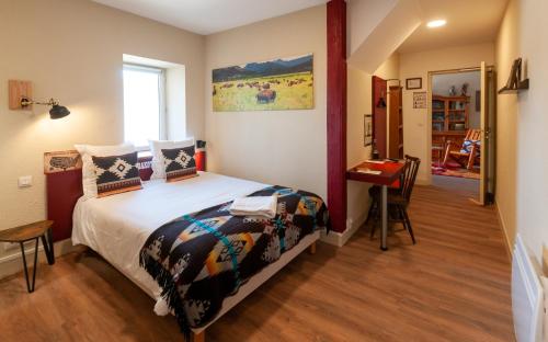 a bedroom with a bed and a table in it at Hotel Le Ranch in Brûlon