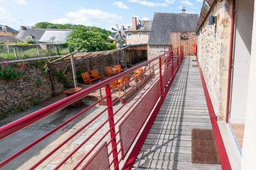 a balcony with a red railing and chairs on a building at Hotel Le Ranch in Brûlon