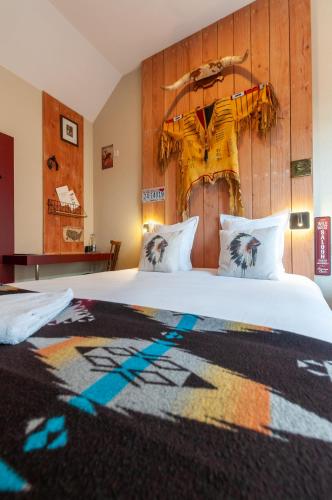 a bedroom with a large white bed with a wooden headboard at Hotel Le Ranch in Brûlon