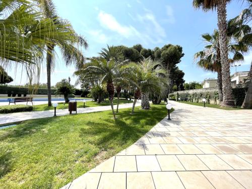 un parque con palmeras y una pasarela en LuxuryCambrils Resort&Spa en Cambrils