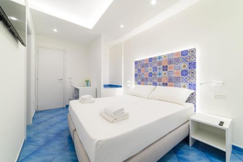 una camera bianca con letto bianco e pavimenti blu di La Dimora del Maestro ad Amalfi
