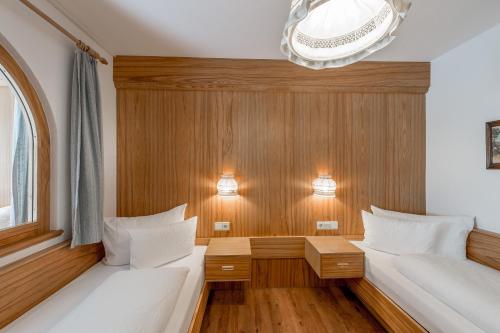 two beds in a room with wood paneling at Apart Hotel Garni Wieser in Sölden