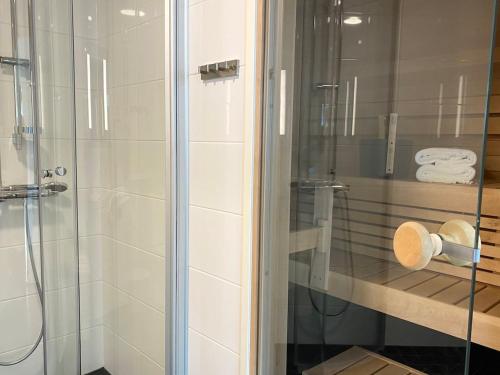 um chuveiro com uma porta de vidro e algumas toalhas em Goldfinger saunallinen kaksio merinäköalalla 11 krs em Helsinque