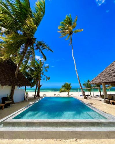 a swimming pool on the beach with palm trees at White Dream in Kiwengwa