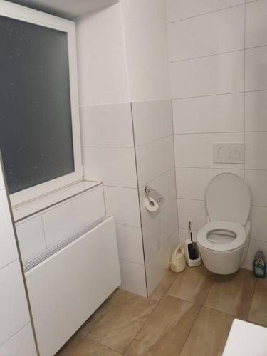 a white bathroom with a toilet and a window at ST2 Apartment in Triberg