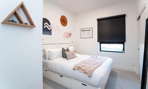a bedroom with a white bed and a flat screen tv at Summit Place - Condo With Mountain Views in Revelstoke