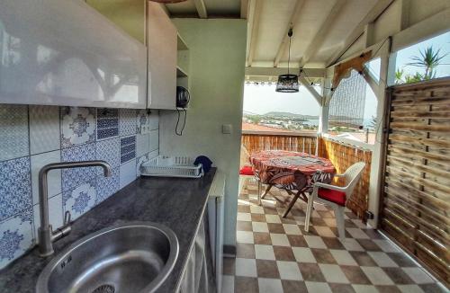 uma cozinha com um lavatório e uma mesa numa varanda em Studio Frangipani dans Villa Fleurs des Iles em Le Vauclin
