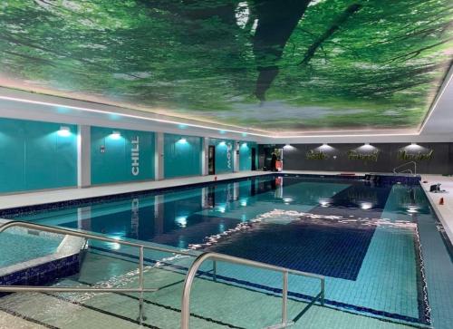 a large indoor swimming pool with a ceiling with a painting at Detached Bungalow in North Cornwall in Bodmin