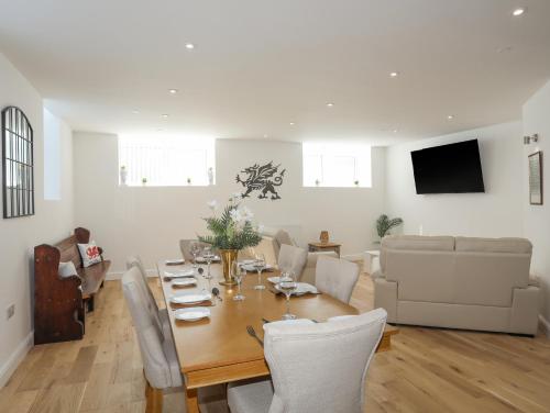 a dining room and living room with a table and chairs at The School House in Holyhead