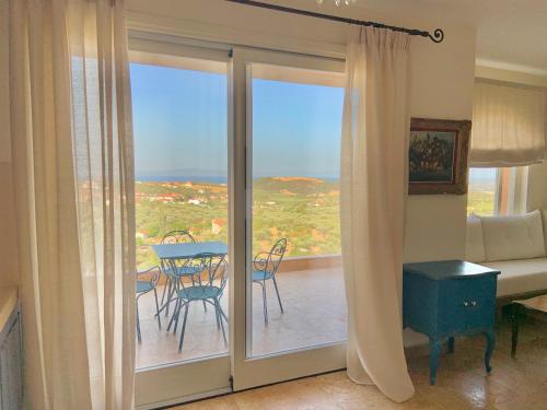 a living room with a sliding glass door with a table and chairs at ST NIKOLA PANORAMIC SUITES HALKIDIKI in Ayios Nikolaos Sithonia