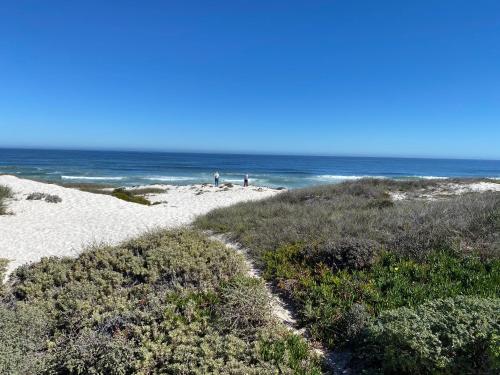a beach with people on the sand and the ocean at Thyme & Tide Beach Villa in Yzerfontein
