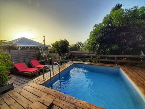 een zwembad op een terras met twee stoelen ernaast bij Appartement Papay dans Villa Fleurs des Iles in Le Vauclin