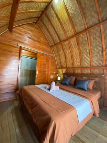 1 dormitorio con 1 cama en una habitación con paredes de madera en D'Yoga Bamboo House, en Kintamani