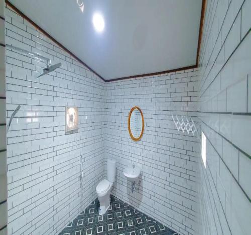 a white bathroom with a toilet and a mirror at Palma Beach Resort in Padangnegeri