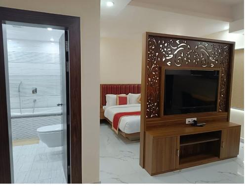 um quarto com uma cama, uma televisão e uma casa de banho em Hotel Paramveer em Muzaffarpur