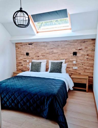 een slaapkamer met een groot bed en een bakstenen muur bij Hotel L'ermitage in Houffalize