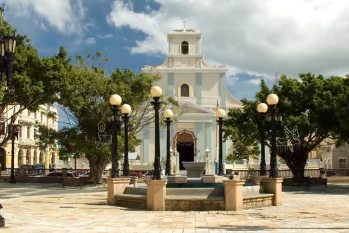 a white building with a fountain in front of it at Family-Home-Workplace-Peace in Arecibo