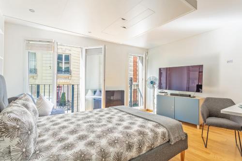 - une chambre avec un lit, une télévision et quelques fenêtres dans l'établissement Arc de Triomphe Luxury Place, à Paris