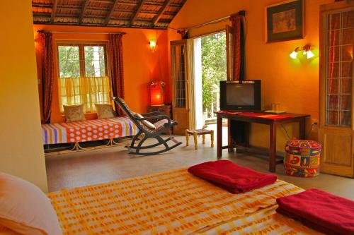 a bedroom with an orange room with a bed and a desk at Michèle's Garden in Anjuna