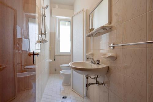 a white bathroom with a sink and a toilet at Hotel Stella Del Mare in Cervia