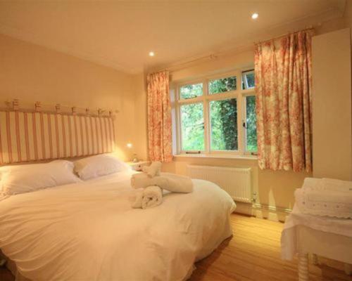 a bedroom with a white teddy bear sitting on a bed at The Cottage Hankerton Priory in Hankerton
