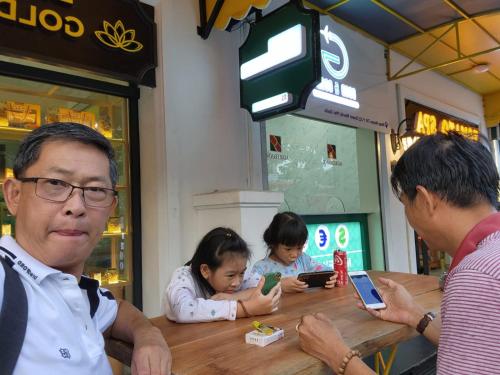 a group of people sitting at a table with their cell phones at Golden Lotus Homestay Phú Quốc in Phu Quoc