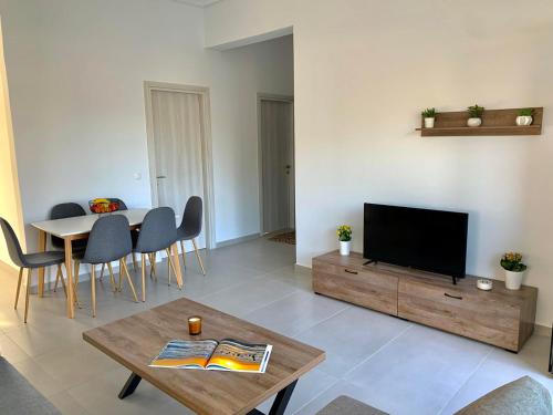 Lýria Boutique Apartments في ليغيا: غرفة معيشة فيها تلفزيون وطاولة وكراسي