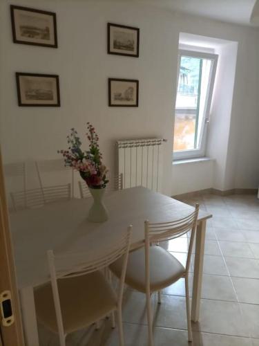 a white dining room table with a vase of flowers on it at Appartamento Casa Margi in Ameglia