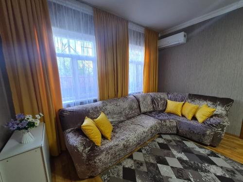 a living room with a couch with yellow pillows at Дачный массив Кайнар Булак. г. Шымкент in Kaynarbulak