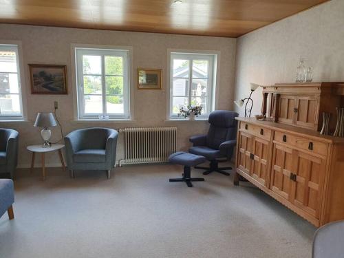 a living room with chairs and a radiator and windows at Mormors idyl in Henne