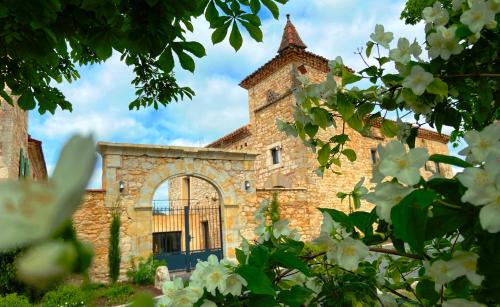 an old stone building with a gate and flowers at DOMAINE DE LEJOS - Portes d'Albi in Lamillarié