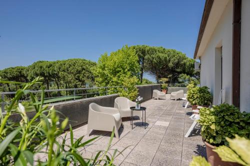 a patio with white chairs and plants on a building at Hotel Stella Del Mare in Cervia