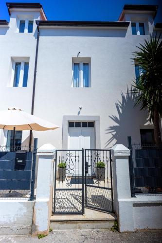 a white house with a gate and a tree at Studio apartments Yucca, 2-min to the beach and 5 to Trogir in Trogir