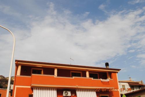un edificio naranja con un cielo nublado en el fondo en La Terrazza sul Golfo, en Sennori