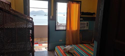 a room with a bedroom with a view of the ocean at ALFA Beach Front Lodge in El Nido