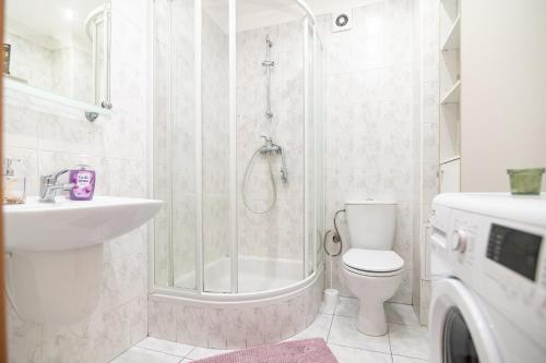 a bathroom with a shower and a toilet and a sink at Regem Pokoje Nowogrodzka in Warsaw