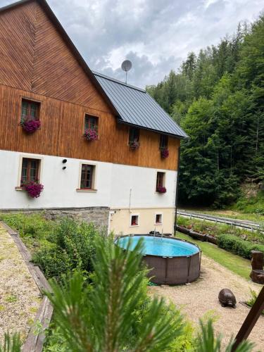 a barn with a swimming pool in front of a house at Hotýlek pod smrkem in Harrachov