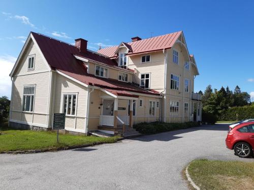 une grande maison avec une voiture rouge garée devant elle dans l'établissement Sörgårdens Logi, à Härnösand