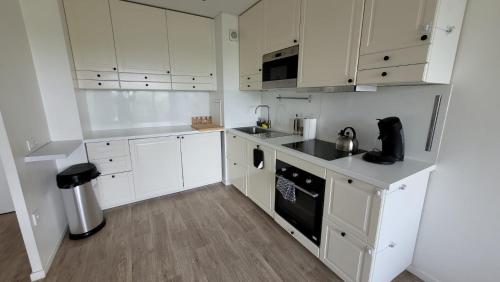a kitchen with white cabinets and a stove top oven at Flat for 6 persons 10 minutes from CDG Airport in Le Blanc-Mesnil