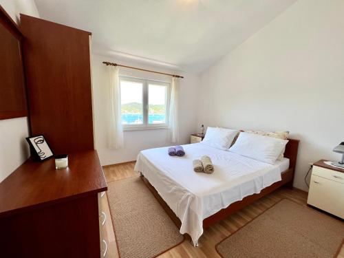 a bedroom with a white bed and a window at Apartment Kustura in Vinišće