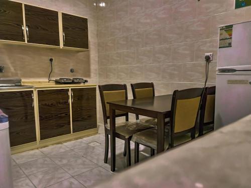 una cucina con tavolo, sedie e frigorifero di الزمردة للشقق المخدومة a Ash Shuqayq