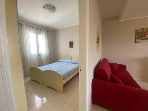 1 dormitorio con 1 cama y 1 sofá rojo en Villetta Sabbia d'Oro en Torre Mozza