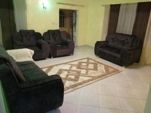 a living room with three couches and a rug at Mwamba Homes in Kisii