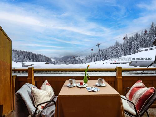 a table and chairs with a view of a snow covered mountain at Berghaus Koglmoos in Auffach