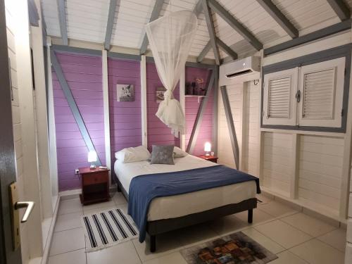 Saint-Louis的住宿－Fleur d'Hibiscus，一间拥有紫色墙壁的卧室和一张位于客房内的床