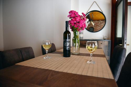 a table with a bottle of wine and two glasses at Kuća za odmor Čanić gaj in Gospić